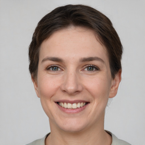 Joyful white young-adult female with short  brown hair and grey eyes