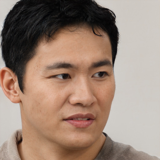 Joyful asian young-adult male with short  brown hair and brown eyes