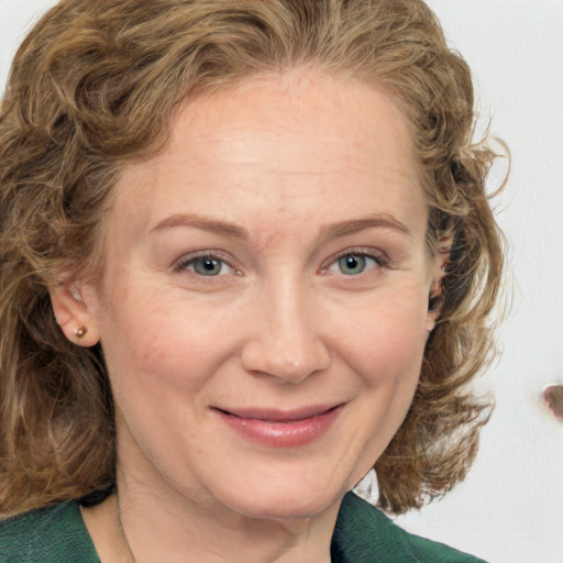 Joyful white adult female with medium  brown hair and green eyes