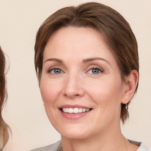 Joyful white adult female with medium  brown hair and blue eyes