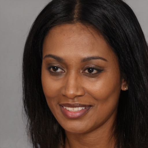 Joyful black young-adult female with long  brown hair and brown eyes
