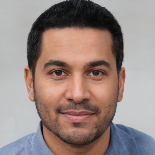 Joyful latino young-adult male with short  black hair and brown eyes