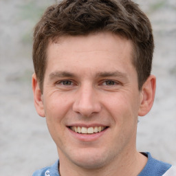 Joyful white young-adult male with short  brown hair and grey eyes