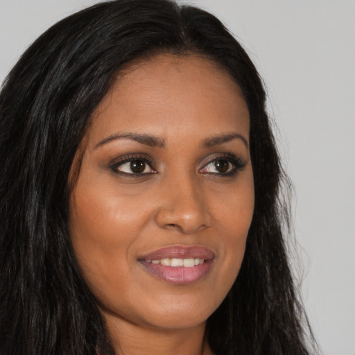 Joyful black young-adult female with long  brown hair and brown eyes
