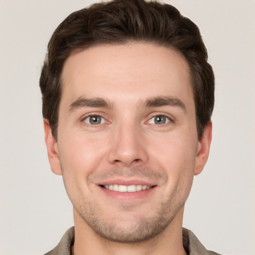 Joyful white young-adult male with short  brown hair and grey eyes