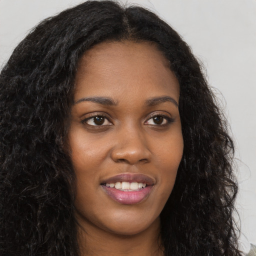 Joyful black young-adult female with long  brown hair and brown eyes