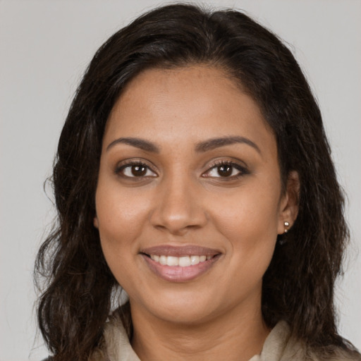 Joyful black young-adult female with long  brown hair and brown eyes