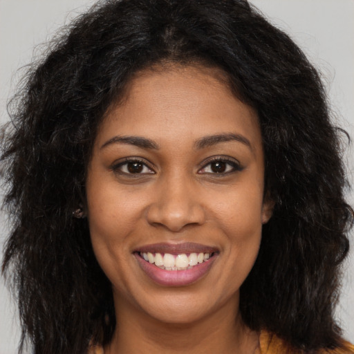 Joyful black young-adult female with long  brown hair and brown eyes