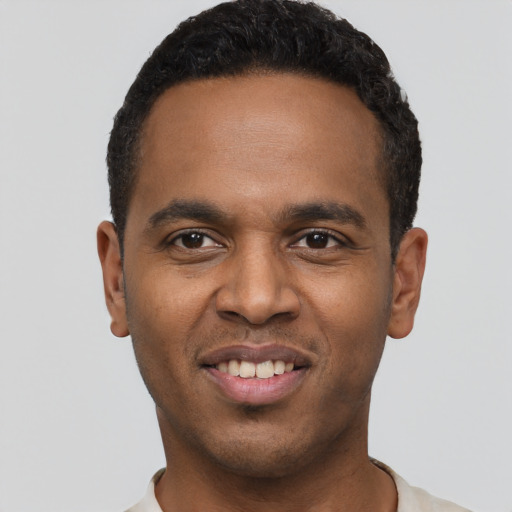 Joyful black young-adult male with short  black hair and brown eyes