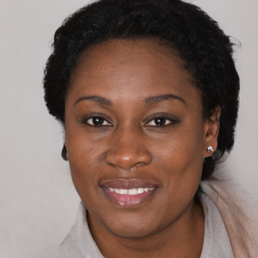 Joyful black young-adult female with short  black hair and brown eyes