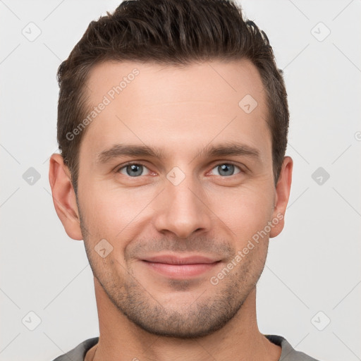 Joyful white young-adult male with short  brown hair and grey eyes