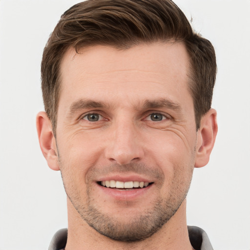 Joyful white young-adult male with short  brown hair and grey eyes