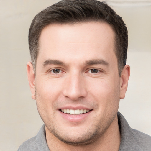 Joyful white young-adult male with short  brown hair and grey eyes