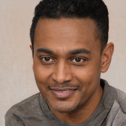 Joyful black young-adult male with short  black hair and brown eyes