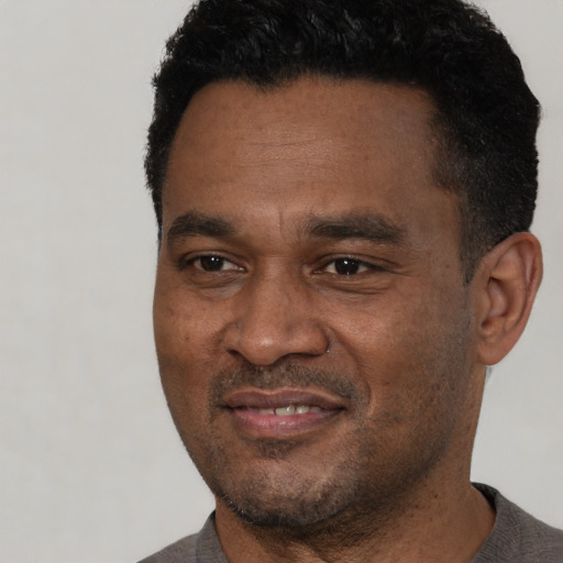 Joyful black adult male with short  black hair and brown eyes