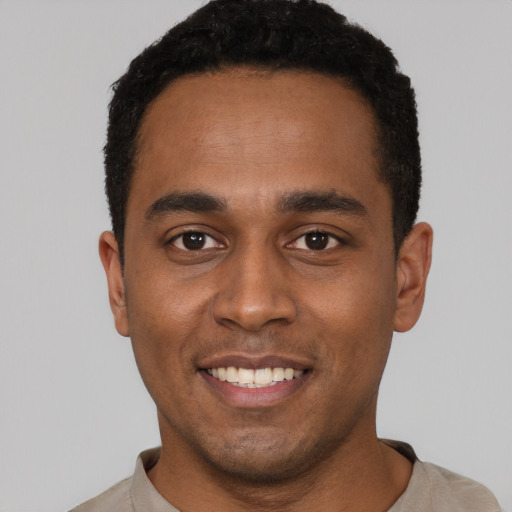 Joyful black young-adult male with short  black hair and brown eyes