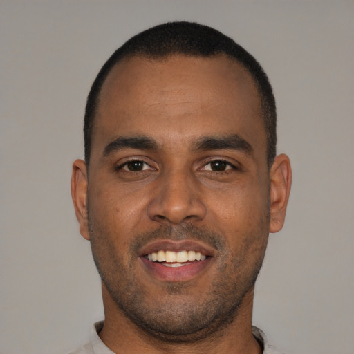 Joyful black young-adult male with short  brown hair and brown eyes