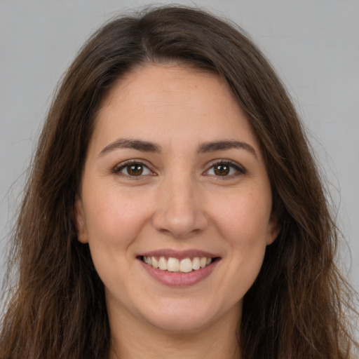 Joyful white young-adult female with long  brown hair and brown eyes