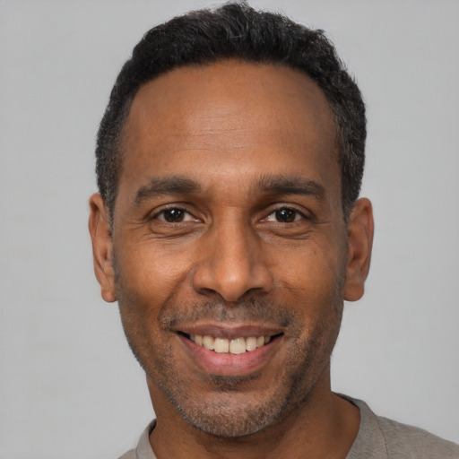 Joyful black adult male with short  black hair and brown eyes