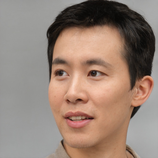 Joyful asian adult male with short  black hair and brown eyes