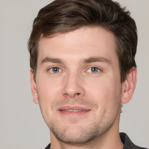 Joyful white young-adult male with short  brown hair and grey eyes