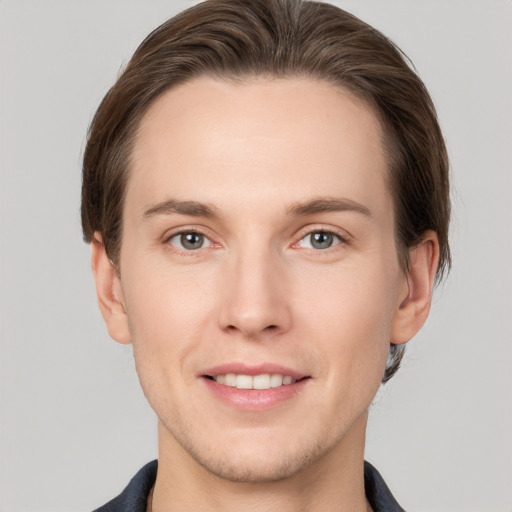 Joyful white young-adult male with short  brown hair and grey eyes