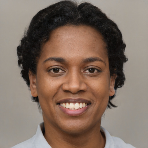 Joyful black young-adult female with short  black hair and brown eyes