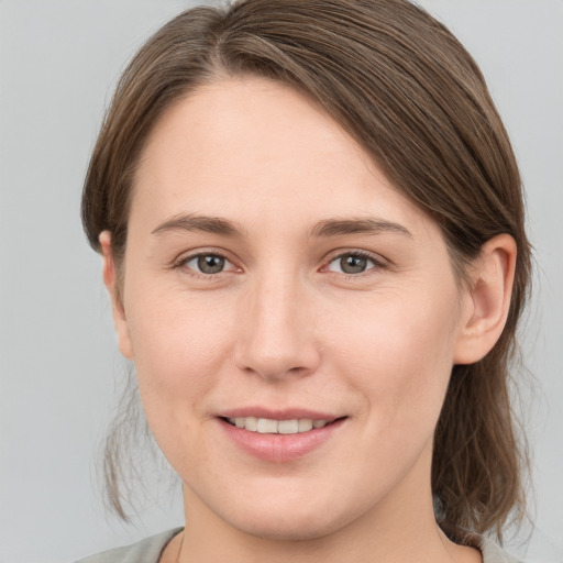 Joyful white young-adult female with medium  brown hair and grey eyes