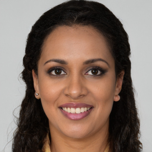 Joyful black young-adult female with long  brown hair and brown eyes