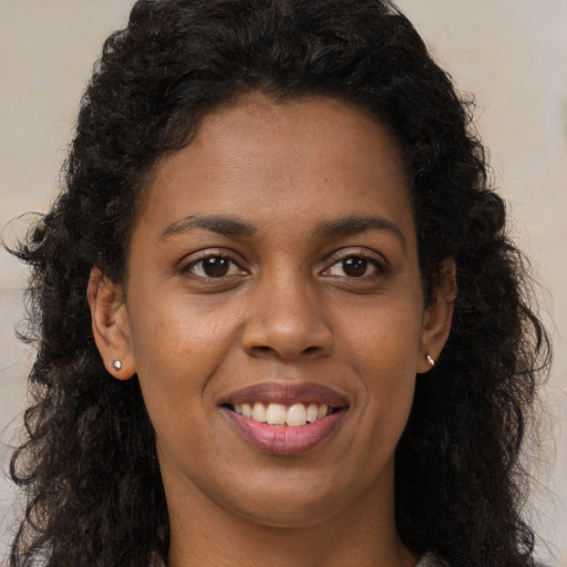 Joyful black young-adult female with long  brown hair and brown eyes
