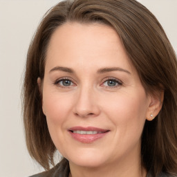 Joyful white adult female with long  brown hair and grey eyes