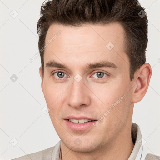 Joyful white young-adult male with short  brown hair and grey eyes