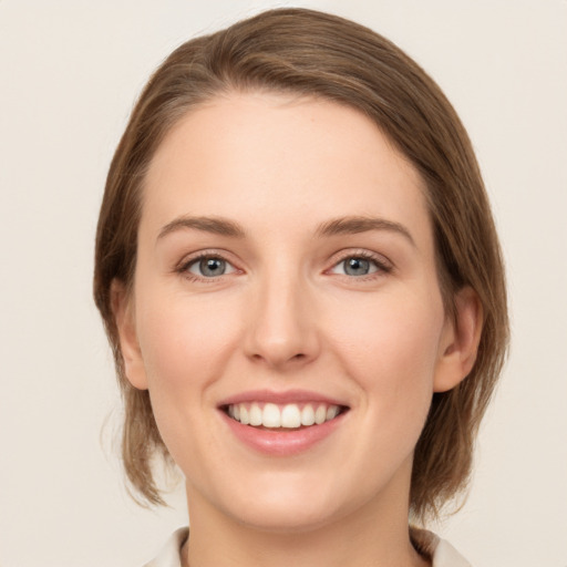 Joyful white young-adult female with medium  brown hair and grey eyes