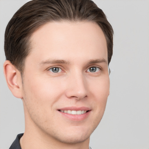 Joyful white young-adult male with short  brown hair and grey eyes