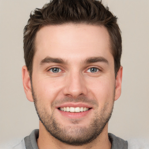 Joyful white young-adult male with short  brown hair and grey eyes