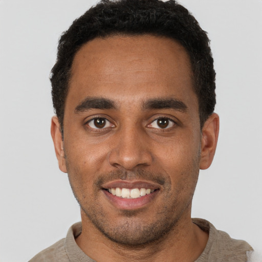 Joyful black young-adult male with short  brown hair and brown eyes