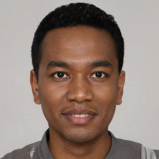 Joyful black young-adult male with short  black hair and brown eyes