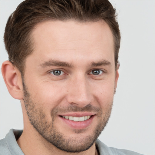 Joyful white young-adult male with short  brown hair and grey eyes