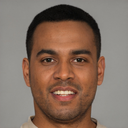 Joyful black young-adult male with short  black hair and brown eyes