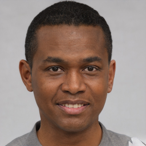 Joyful black young-adult male with short  brown hair and brown eyes