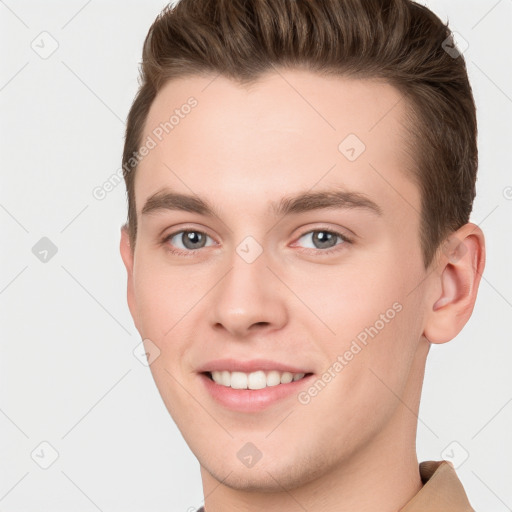 Joyful white young-adult male with short  brown hair and grey eyes