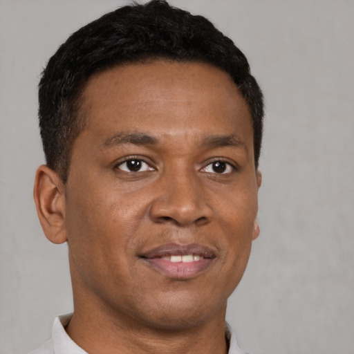 Joyful black young-adult male with short  brown hair and brown eyes