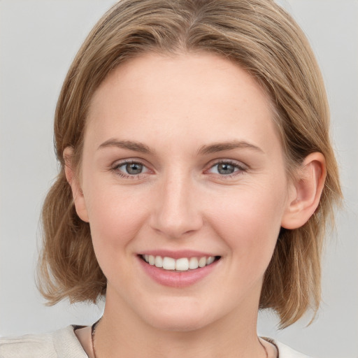 Joyful white young-adult female with medium  brown hair and blue eyes