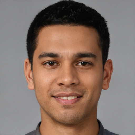 Joyful latino young-adult male with short  black hair and brown eyes