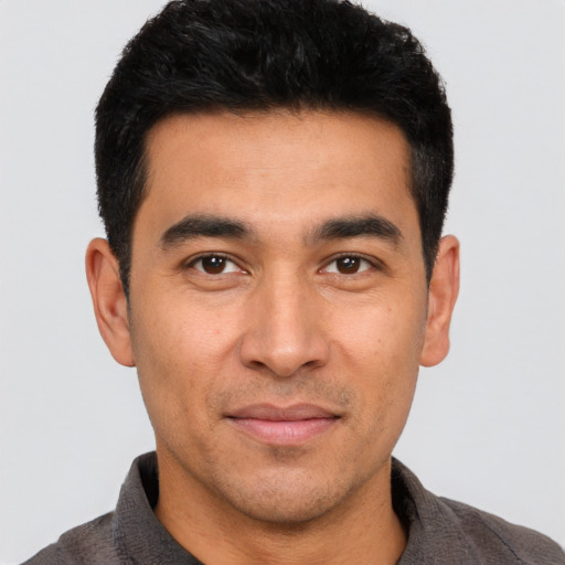 Joyful latino young-adult male with short  black hair and brown eyes