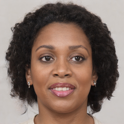Joyful black adult female with medium  brown hair and brown eyes