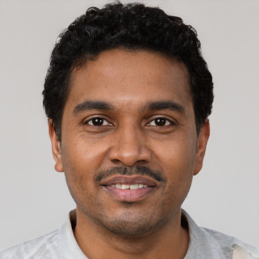 Joyful black young-adult male with short  black hair and brown eyes