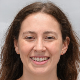 Joyful white adult female with long  brown hair and grey eyes