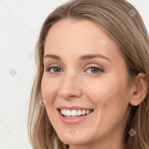 Joyful white young-adult female with long  brown hair and blue eyes