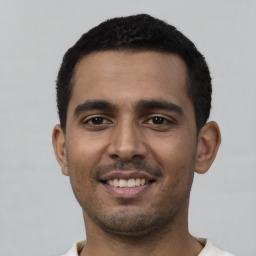 Joyful latino young-adult male with short  black hair and brown eyes